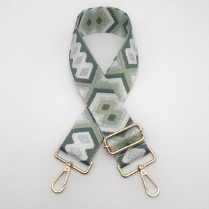 Detail of grey geometric woven bag strap with golden metal lobster clasps and buckle