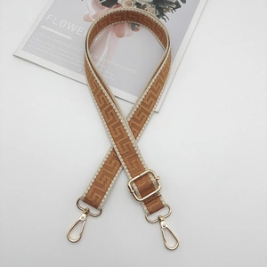 Detail of adjustable bag strap with jacquard geometric pattern and gold hardware