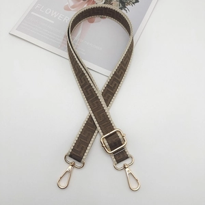 Close-up of adjustable woven strap with dark floral patterns and gold metal lobster clasps