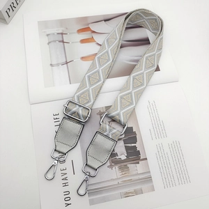 Macro detail of wide jacquard geometric bag strap with polished silver metal swivel hook