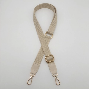 Detail of adjustable geometric woven bag strap with golden buckles and PU leather ends