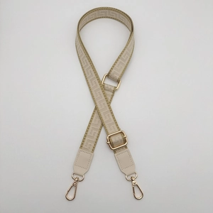 Detail of geometric pattern woven bag strap with adjustable gold metal buckles