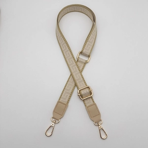 Detail of adjustable geometric jacquard bag strap with gold metal hooks and leather accents