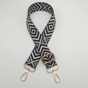Détail de la bandoulière en toile à motif losange avec boucle dorée réglable et mousquetons