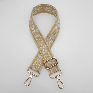Detailaufnahme von gelbem Ethno-Taschengurt mit goldenen Metallhaken und floralem Webmuster