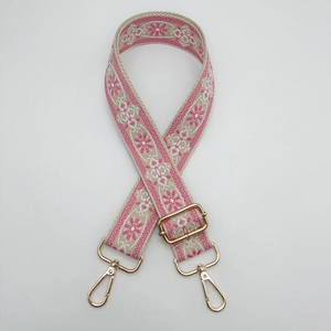 Detail eines bestickten Schultergurts mit floralem Muster und goldenen Karabinerhaken
