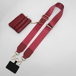 Detail view of burgundy wide shoulder strap with matching mini pouch and gold hardware