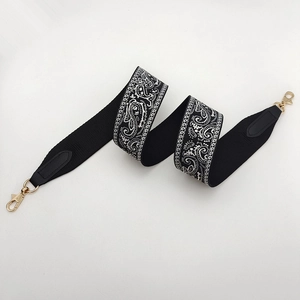 Close-up of woven paisley pattern shoulder strap with black leather ends and gold hardware