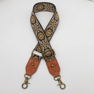 Detail of bohemian patterned woven strap with brown leather ends and bronze metal clasps