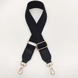 Detail of black geometric pattern woven bag strap with golden metal lobster clasps