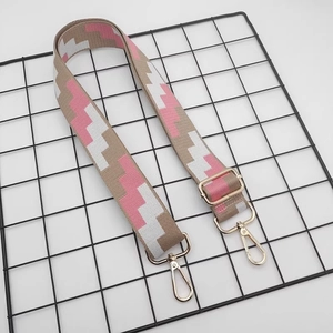 Detail of adjustable wide canvas shoulder strap with pink geometric pattern and gold buckles