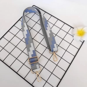 Close-up of adjustable canvas bag strap with geometric patterns and gold metal buckles