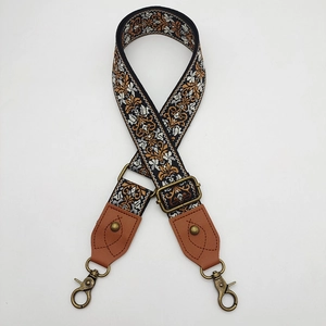 Close-up of vintage ethnic embroidery bag strap with bronze metal hooks and brown leather