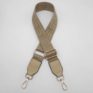 Close-up of adjustable khaki wide shoulder strap with Greek key pattern and gold hardware