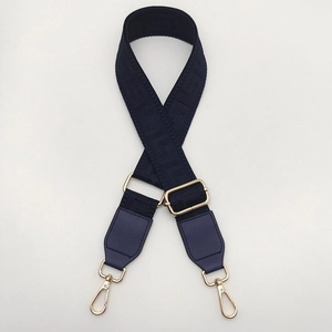Detail of blue jacquard bag strap with geometric patterns and gold metal lobster clasps