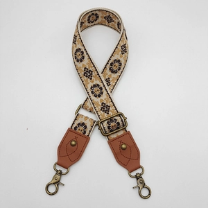 Close-up of vintage ethnic floral jacquard bag strap with bronze hooks and leather ends