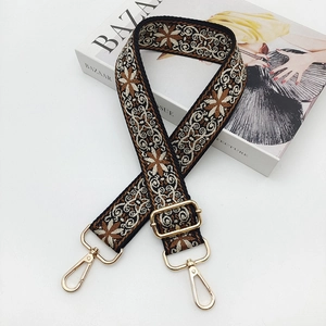 Close-up of bohemian geometric jacquard bag strap with gold metal hardware on magazine