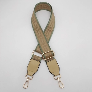 Detail view of adjustable wide jacquard bag strap with geometric patterns and gold metal buckles