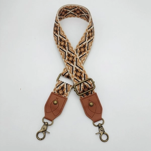 Close-up of bohemian geometric woven bag strap with brown leather and bronze hooks