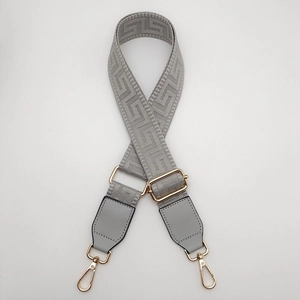 Detail of grey Greek key pattern strap with golden metal swivel hooks and buckles