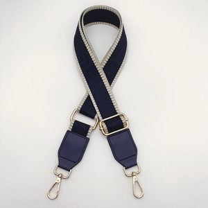 Detail of dark blue geometric pattern bag strap with gold metal lobster clasps