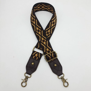 Detail of bohemian geometric woven bag strap with bronze metal hooks and leather ends