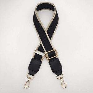 Detail of adjustable black weave bag strap with gold metal hooks and geometric patterns