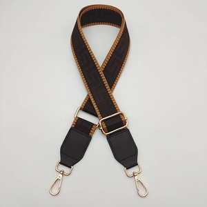 Detail of adjustable geometric patterned bag strap with golden swivel lobster hooks