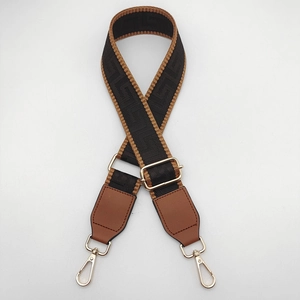 Close-up of a wide 3.8cm woven bag strap with geometric patterns and gold metal hooks