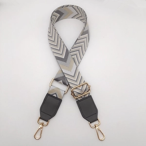 Detail of adjustable woven canvas strap with grey wave pattern and gold metal hooks