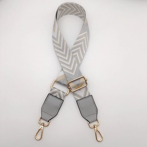 Close-up of adjustable wide canvas bag strap with chevron weaving and metal hooks