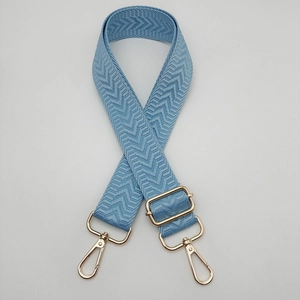 Détail de la bandoulière tissée bleu clair avec mousquetons dorés et boucle réglable