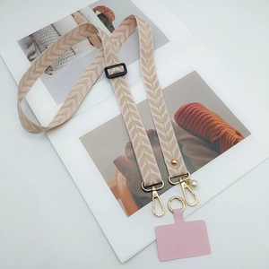 Close-up of pink woven phone lanyard with golden hook, pearl charm and insert pad