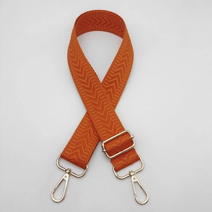 Détail d'une bandoulière orange réglable avec motif en V et mousquetons métalliques