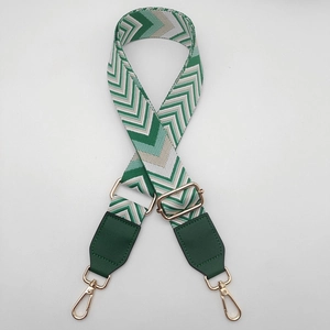 Detail of adjustable green and white canvas bag strap with gold metal hooks
