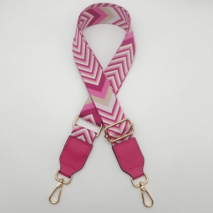 Detail of adjustable canvas bag strap with pink chevron pattern and gold metal hooks