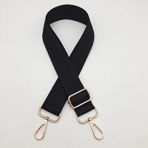 Détail de la bandoulière noire à chevrons avec mousquetons rotatifs en métal doré
