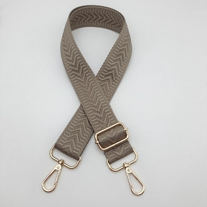 Détail de la bandoulière réglable beige avec texture chevrons et crochets en métal doré