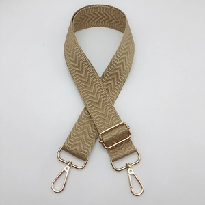Détail de la bandoulière large tissée beige avec mousquetons et boucle en métal doré