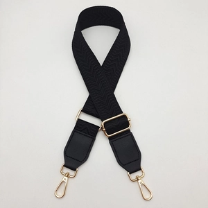 Detail view of black herringbone woven canvas strap with golden rotating lobster clasps