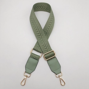 Detail of adjustable green arrow weave canvas strap with gold metal hooks and leather trim