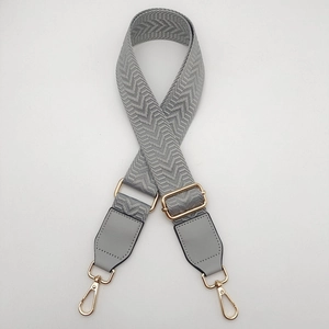 Detail of grey herringbone pattern canvas bag strap with gold metal lobster clasps