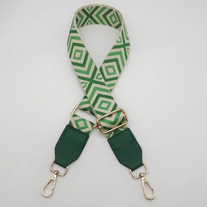 Detail of green diamond pattern wide canvas strap with gold metal buckles and green leather hooks