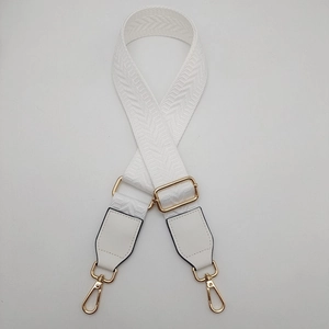 Detail of white herringbone canvas bag strap with golden metal hardware and lobster clasps