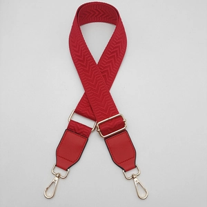 Detail of red chevron canvas bag strap with golden metal hooks and adjustable buckle