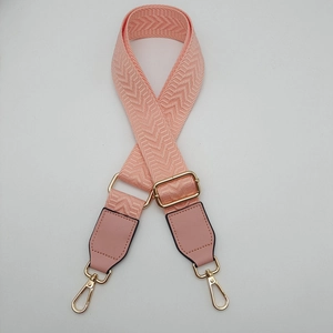 Close-up of pink canvas bag strap with chevron texture and golden metal spring hooks