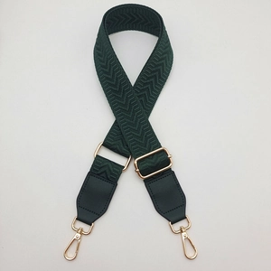 Detail of dark green herringbone nylon strap with gold metal lobster clasps and leather ends