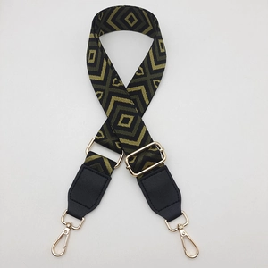 Detail of adjustable wide canvas shoulder strap with green diamond jacquard and gold clips