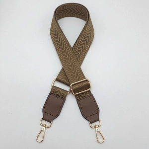 Close-up of brown chevron woven bag strap with leather ends and golden metal snap hooks