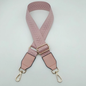 Close-up of pink herringbone woven strap with golden swivel metal hooks and leather detail
